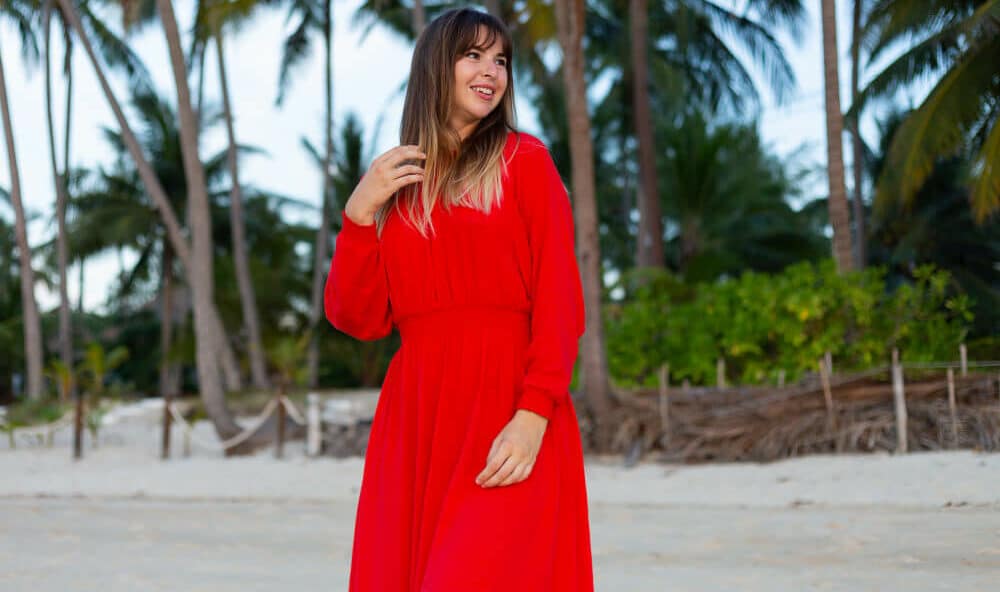 robe grande taille pour femme de Miss Pareo. La robe est rouge sur fond de plage