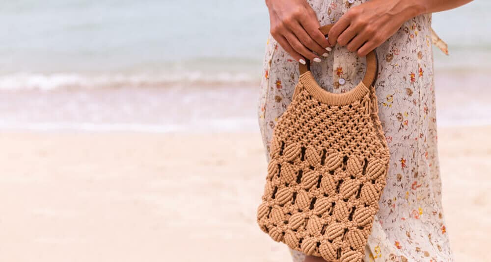 Le sac raphia de Miss Pareo. Le sac est en raphia, il est marron sur fond de plage et mer bleu