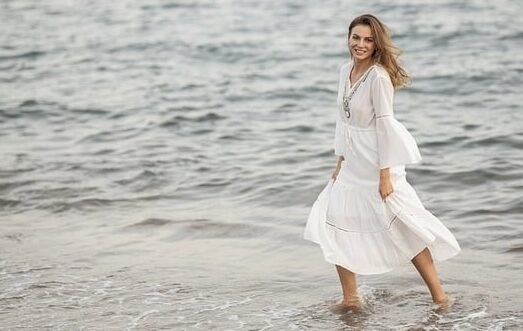 la robe longue en couleur blanc de la collection miss pareo portée par un mannequin sur la plage